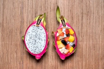 Fruit salad in dragonfruit on wood background