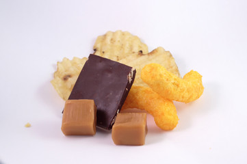 Caramels, chocolate, rippled chips and cheese puffs on a white background