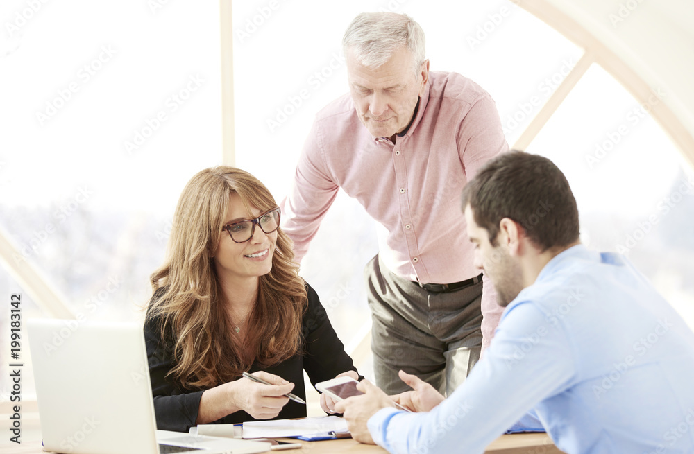 Sticker Close-up ofmiddle aged businesswoman consulting with senior manager and young assistant while sitting at office desk and working together on new project. Teamwork. 