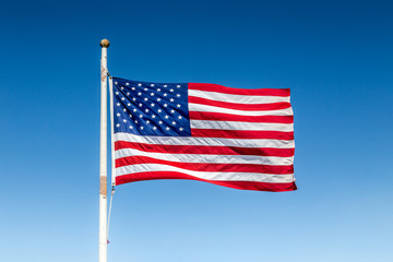 Fototapeta premium USA flag waving in the wind against blue sky on a sunny day