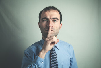 Caucasian man making silence gesture.