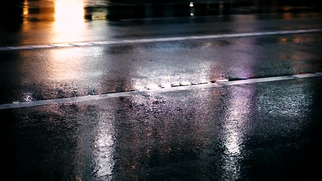 雨の日、夜の道路のアスファルトに反射する都市のネオン