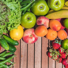 Various vegetables and fruits on a wooden tray against a background of green grass