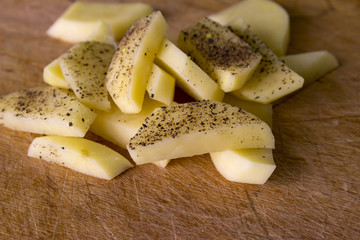 Raw potatoes sliced for cooking French fries in a rustic manner.