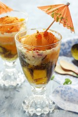 Homemade Mango Falooda topped with Tutti Frutti and cocktail Umbrella, selective focus