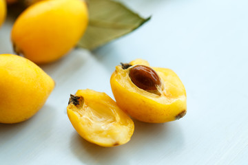 Loquat orange fruits on branch with leaves on a blue wooden background