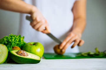 green fruits on front. woman cut fruits on background. healthy food concept