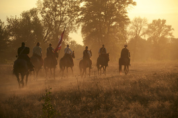 Fototapeta na wymiar horseriders galloping in the field on the sunset