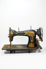 An old antique sewing machine, decorated with golden ornaments. Vertical frame.