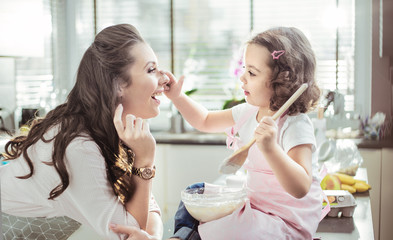Pretty mother and her daughter preparing a cake