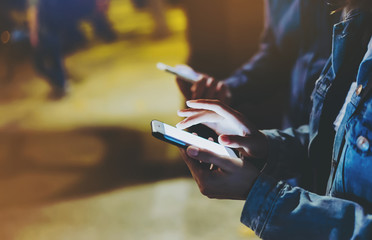 Group adult hipsters friends using in hands modern mobile phone, street online wi-fi internet concept, bloggers together pointing finger on screen smartphone on background bokeh light in night city