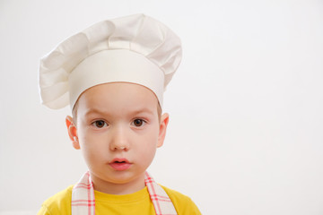 Portrait of a child in a cook cap and an apron on a white background