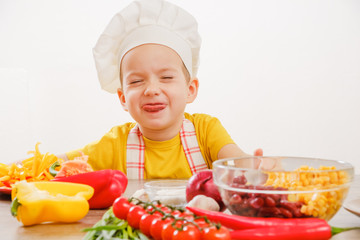 Happy child prepares and eats vegetables in kitchen
