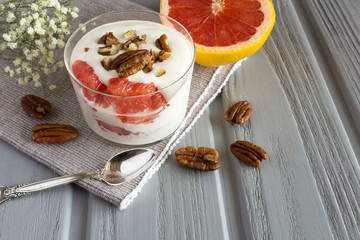 Milk yogurt with grapefruit and pecan nuts  on the grey wooden background