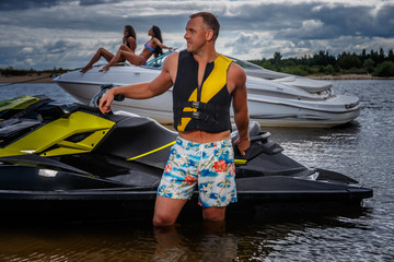 Happy handsome sportsman standing near jet ski on a sea coast.