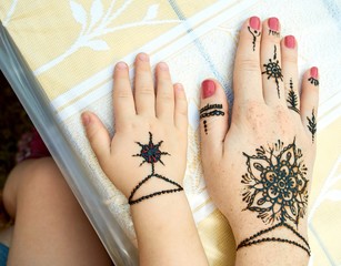 Hands of a mother and child with a traditional indian black flower tattoes