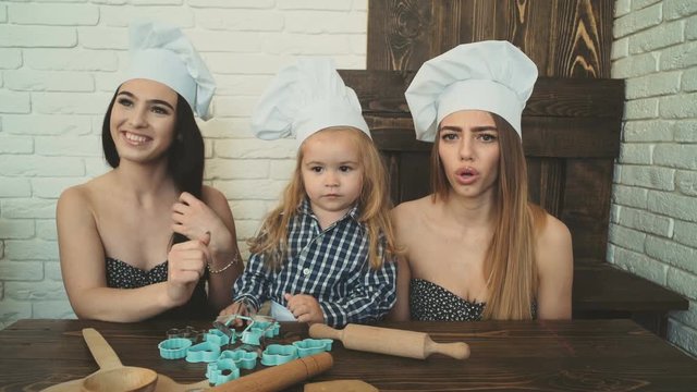 Lesbian couple cooking with their adopted child. Sisters cooking with their younger brother.