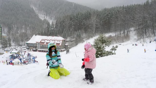 Mom with a three-year-old daughter play snowballs