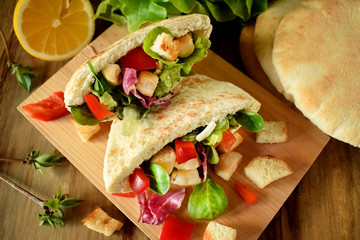 Caesar salad in pita bread on a wooden board
