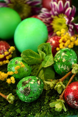 Easter coloured eggs surrounded by flowers on grass