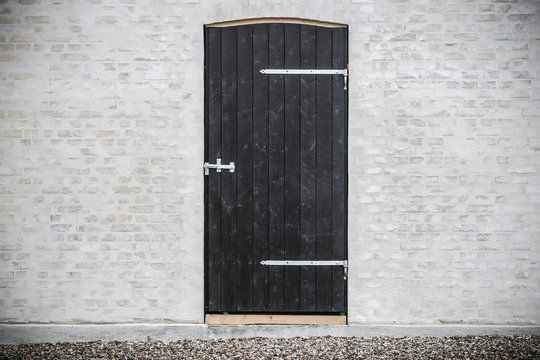 Black wooden door on a grey brick wall