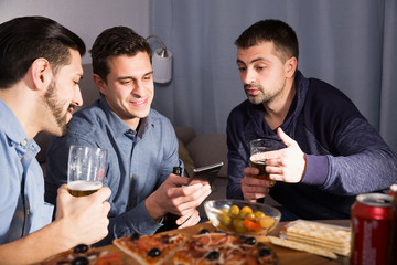 friends looking at phone while drinking beer