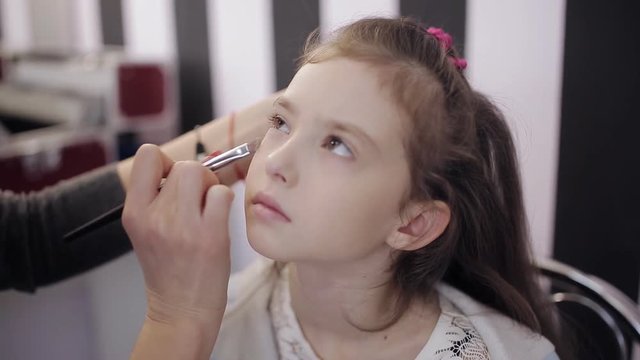 master makeup artist paints the eyes of the little girl