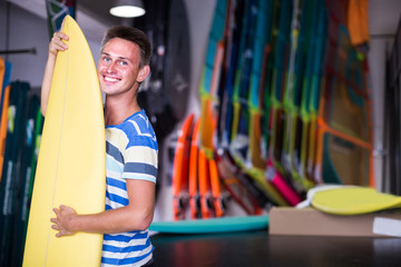 male is posing with surfboard in store on the beach.