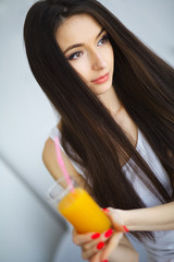 Cheerful woman drinking an orange juice sitting on her bed at home