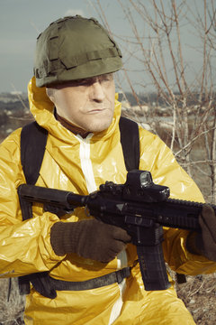 Freak gunman afraid of atomic war in yellow overall watching noticeably around