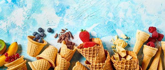 Wafer cones filled with fruits on blue background