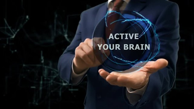 Businessman shows concept hologram Active your brain on his hand. Man in business suit with future technology screen and modern cosmic background