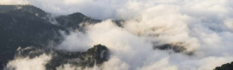 Aerial view on mountaintops covered with clouds during sunrise