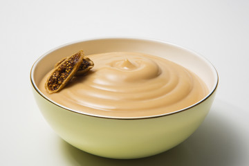 Bowl with tasty pudding on white background. Cream caramel and fig.
