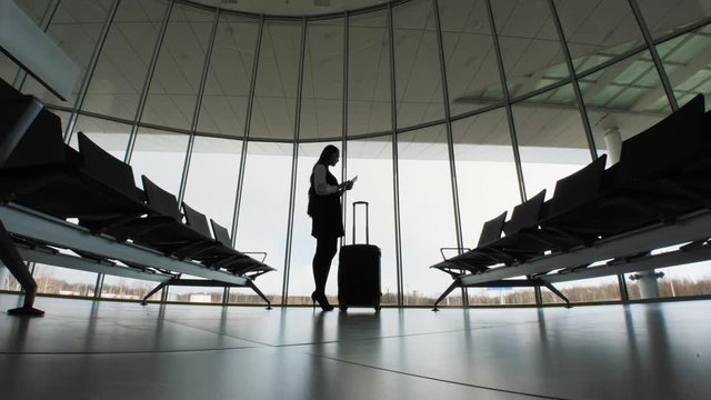 businesswoman at the airport. silhouette of a girl with mobile phone and luggage baggage suitcase, tablet. business and travel woman in terminal office railway bus station