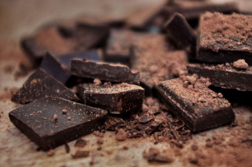 Cocoa powder and Chocolate bar close up. Pile of broken dark chocolate and cocoa powder.