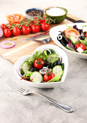 bowl of salad with vegetables and greens, with tomato, cucumber and onions.