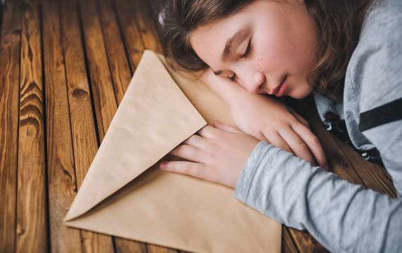 The little girl tiredly put her head on the table next to a large brown envelope. Envelope with a letter of the child with wishes for Christmas. The girl closed her eyes.
