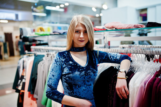 Blonde girl in blue dress in the clothing store boutique.