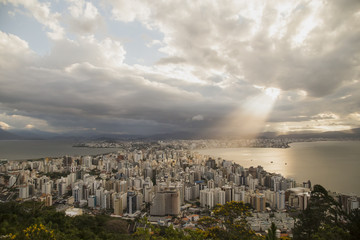 Panoramic view of the city's downtown. Light rays shining over the buildings and the bay. Rain clouds at distance, colorful clouds. Florian&oacute;polis, Santa Catarina / Brazil