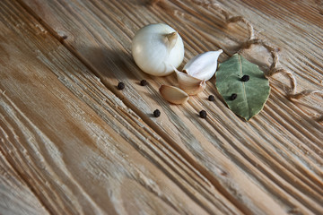onion, garlic, black pepper and bay leaf on a wooden background