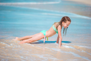 Fototapeta premium Adorable little girl at beach having a lot of fun in shallow water