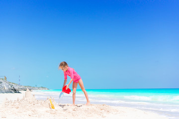 Obraz na płótnie Canvas Adorable little girl playing with beach toys on white tropial beach