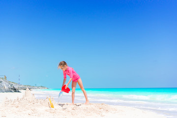 Adorable little girl playing with beach toys on white tropial beach