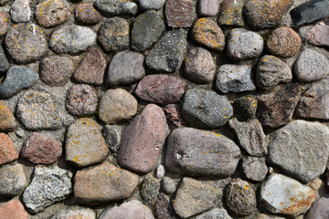 Pattern of grey decorative random sized stones outdoors wall with concrete connection as natural surface background.