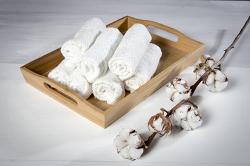 tray with a towel for hand in spa salon and a cotton branch on a white wooden table