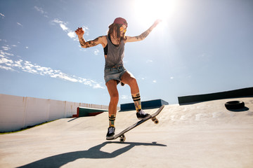 Female skater skateboarding at skate park.