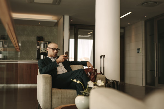 Business traveler waiting in airport lounge using phone