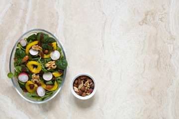 Obraz na płótnie Canvas Healthy vegan salad with radish, nuts, yellow pepper on marble with copy space to right