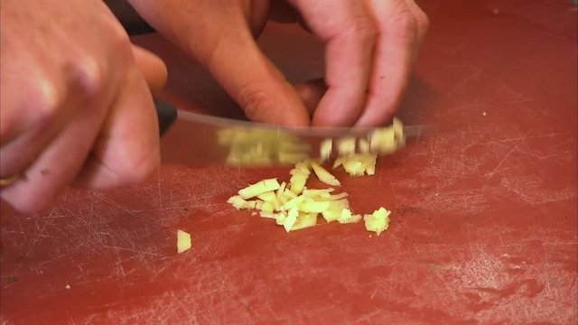 A medium shot of a person chopping garlic